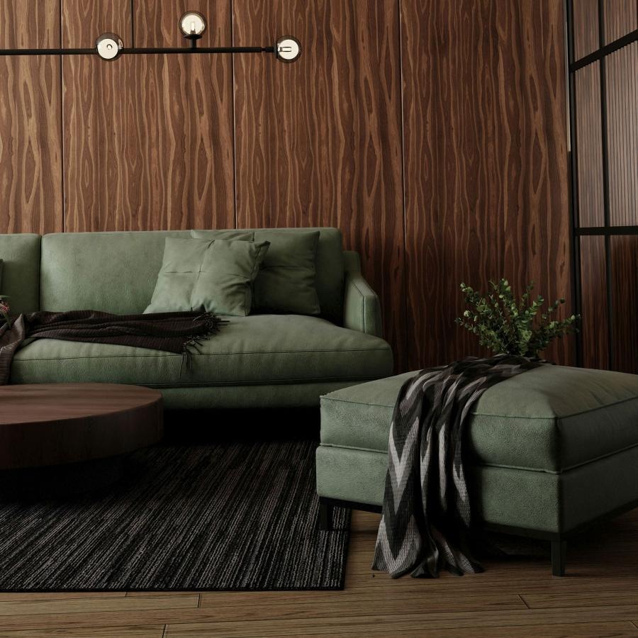 A green couch and a coffee table in a room with a wood wall